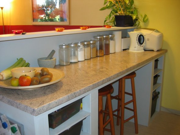 Als praktische Ergänzung zur grauen Einbauküche (vom Vermieter) bietet der Küchentresen viel Platz beim Zubereiten von Essen, eine Menge Stauraum und 