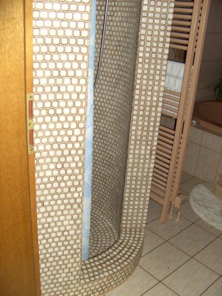 Rund gemauerte Dusche mit Mosaikfliesen gefliest.